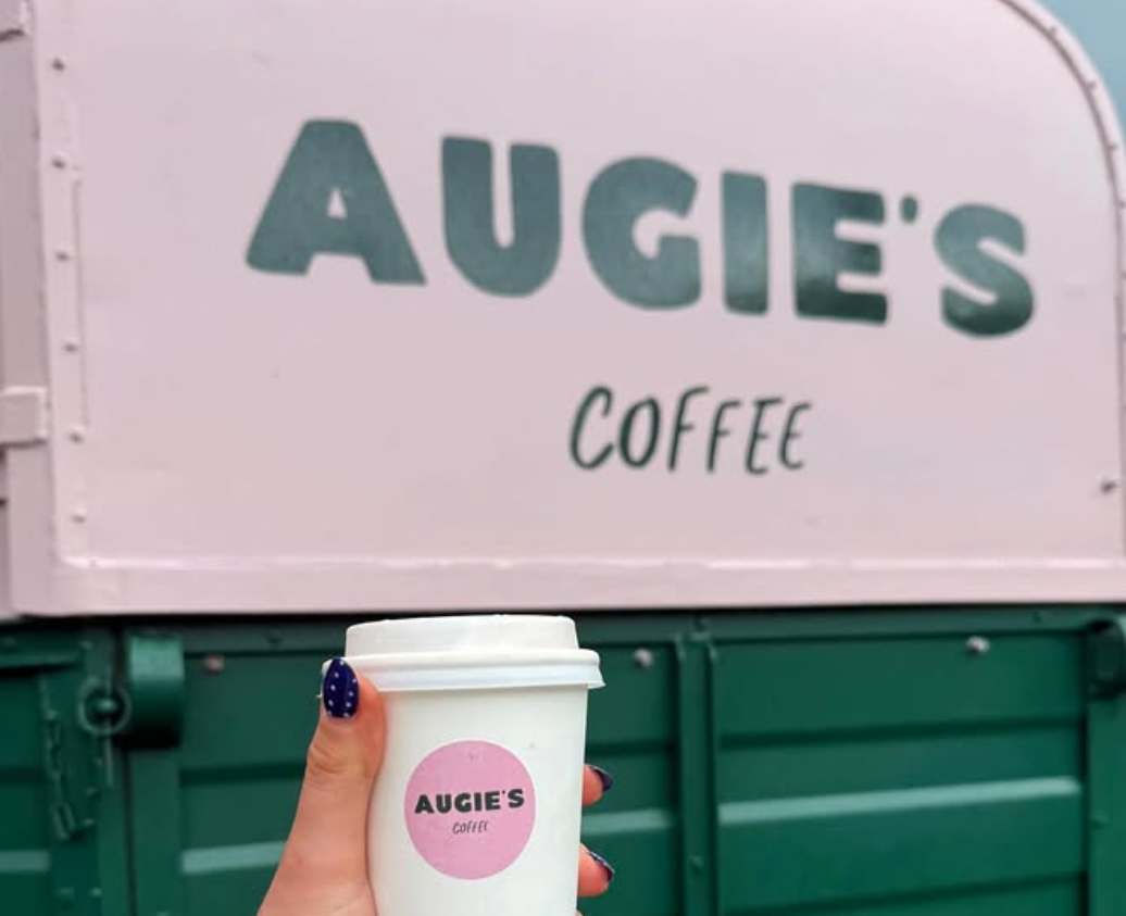 An Augie's takeaway cup held up in front of the van